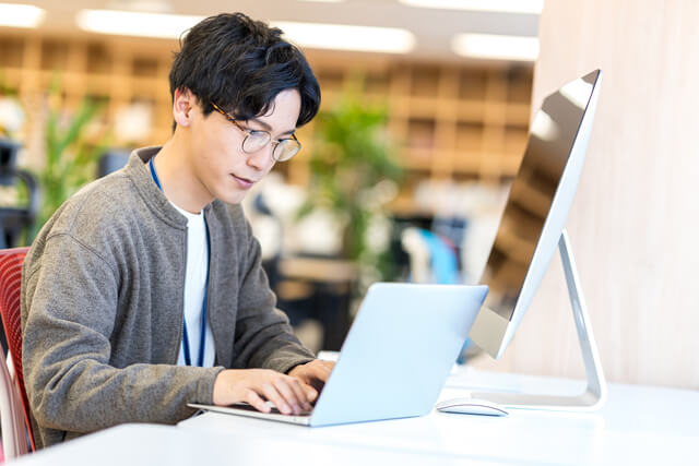 メガネをかけた男性がパソコンでWEBサイトを制作している写真